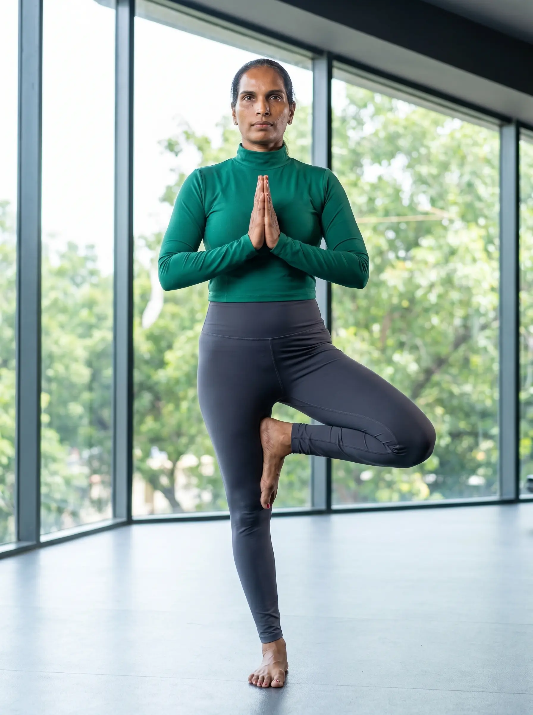 Expert yoga trainer demonstrating Tree Pose for balance during virtual online yoga classes for clients in India.